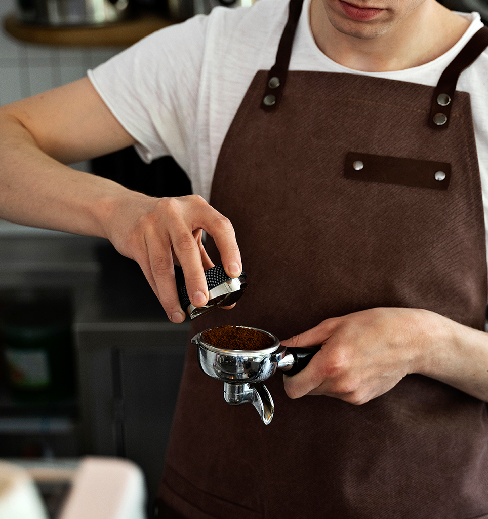 Barista tamping coffee grounds for espresso.