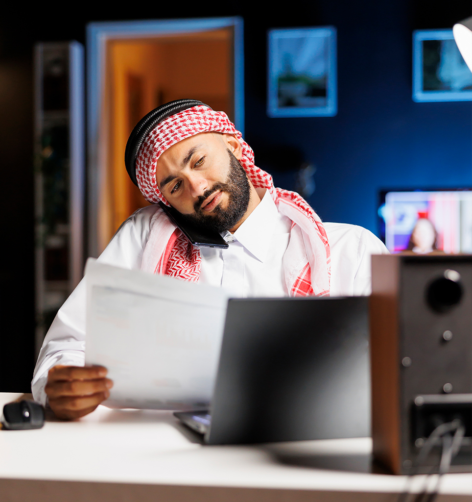 Man working on documents and laptop in KSA.